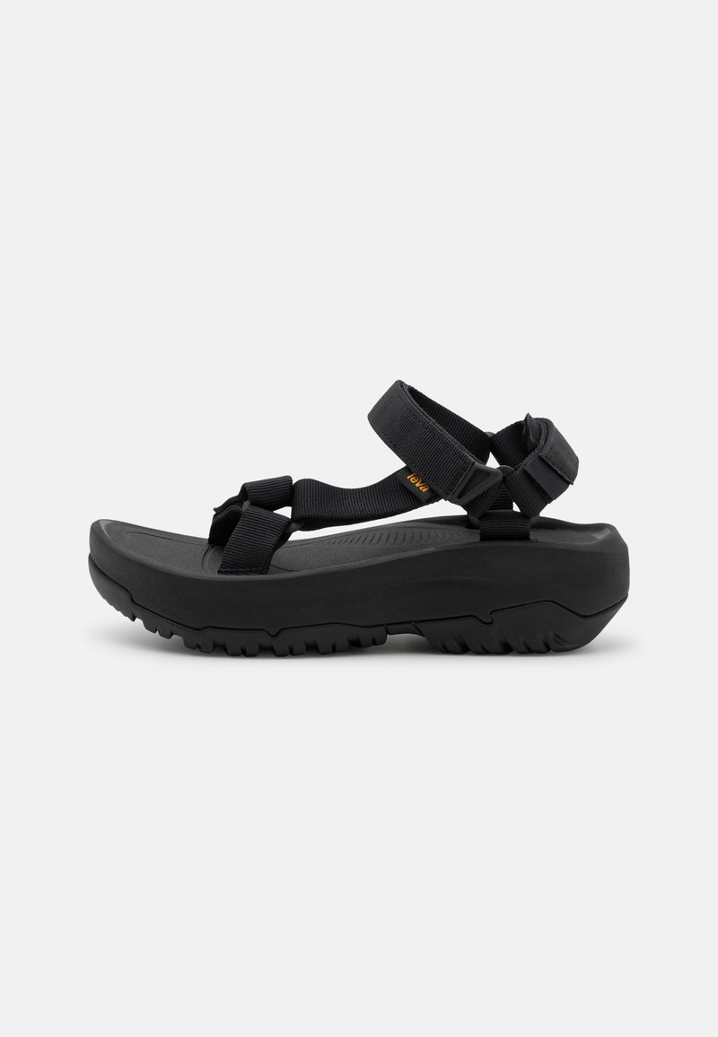 Black sandals with adjustable fabric straps, thick rubber soles, and textured footbeds designed for comfort and grip.