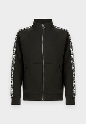 Μαύρο φούτερ με φερμουάρ, κατασκευασμένο από μαλακό ύφασμα, με ψηλό γιακά και λευκές λεπτομέρειες λογότυπου κατά μήκος των μανικιών. Ριμπ μανσέ�τες και τελείωμα.