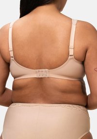 Lichtbeige bh met verstelbare banden en een multi-haak sluiting aan de achterkant. Gladde stof met een kanten accent op de randen van de bijpassende onderbroek.
