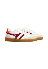 Zapatillas blancas de caña baja con rayas rojas, parche en el talón naranja y suelas de goma, vista lateral en ángulo.
