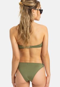 Olivovo zelený bikiny s bandeau topom a vysokým strihom, s hladkou textúrou a minimálnym šitím. Zadný pohľad zdôrazňuje dizajn.