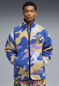 Giacca in pile con motivo mimetico in blu, beige e viola. Presenta una zip frontale, un colletto alto e un ricamo con il logo sul petto.