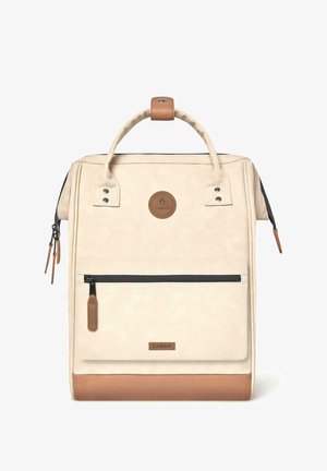 Cremfarbener Rucksack mit strukturierter Oberfläche, ausgestattet mit einem braunen Lederboden, einem oberen Griff und einer Vorderreißverschlusstasche. Markenlogo gut sichtbar.