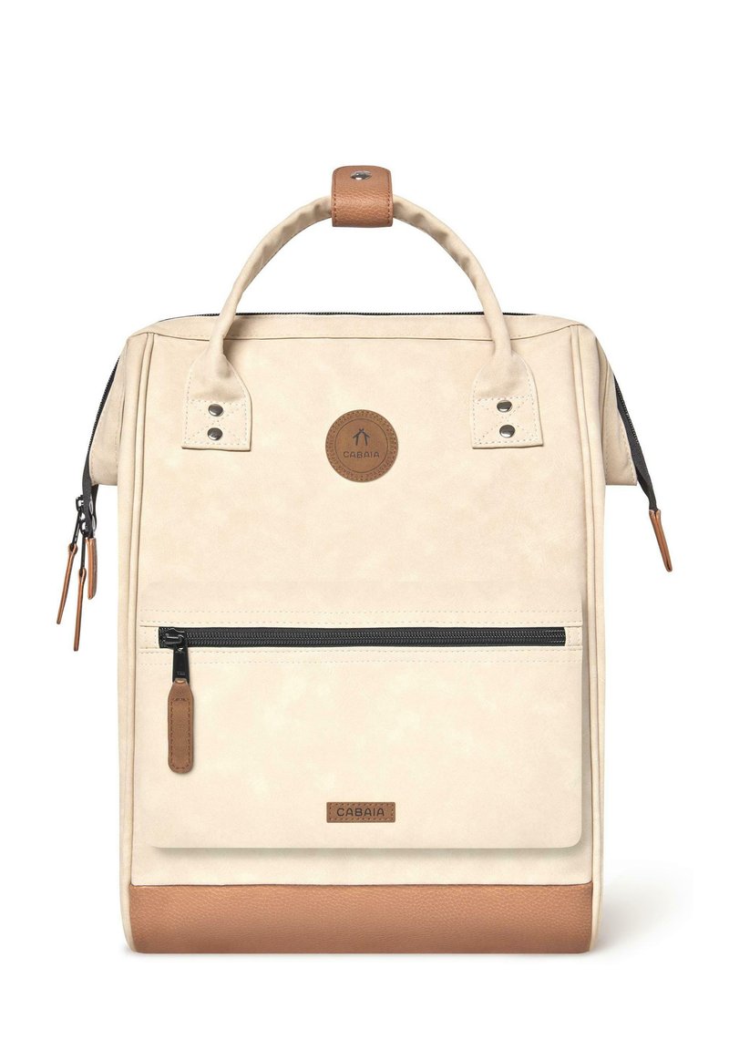 Mochila color crema con un acabado texturizado, que presenta una base de cuero marrón, un mango superior y un bolsillo con cremallera en la parte frontal. Logo de la marca visible.