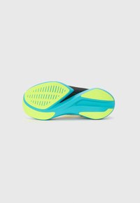 Suela de zapatilla deportiva con parte superior negra, presenta una suela exterior en turquesa y amarillo brillante, texturizada para un mejor agarre con estrías y patrones.