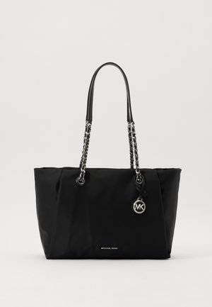 Sort Michael Kors tote taske med sølvkædehåndtag og rundt MK logo vedhæng på ensfarvet baggrund.