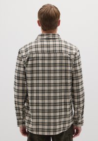 Camisa de franela a cuadros en tonos beige, azul marino y verde. Cuenta con cuello, mangas largas y dobladillo redondeado con puños abotonados.