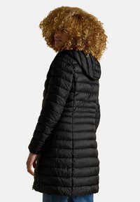 Čierna páperová bunda s kapucňou, s prešívanou textúrou, dlhými rukávmi a dizajnom po kolená. Zipsové vrecká po stranách.