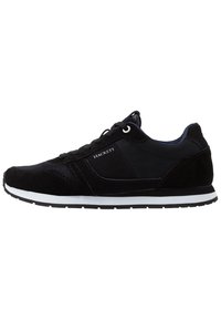 Chaussure de sport noire associant suède et mesh, semelle en caoutchouc blanc et design à lacets avec des détails contrastants.