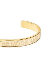 Bracelet en métal doré avec un bracelet rigide comportant une inscription gravée qui dit "JUSQU'À LA LUNE ET RETOUR". Fini lisse et poli.