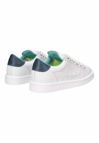 Zapatillas de cuero blancas con un perfil bajo, perforaciones texturizadas en los laterales, acentos en azul marino en el talón y un forro interior de color verde claro.
