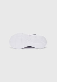 Semelle de chaussure en caoutchouc blanc texturé, arborant des motifs incurvés et des rainures pour l'adhérence. Style minimaliste avec une finition lisse.