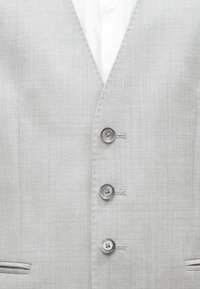 Heledhall hallik ülikonnajakk, millel on kolm nähtavat nuppu ja all valge särk, esitatud lähivaatlusel.