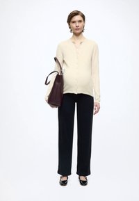 Beige button-up top, black wide-leg pants, and black shoes. Carrying a burgundy leather bag. Simple design with a smooth texture.