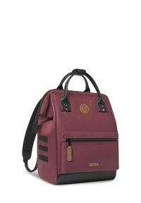 Sac à dos marron avec des accents noirs, en polyester texturé, avec des poignées supérieures, une poche zippée à l'avant et un détail de logo circulaire.
