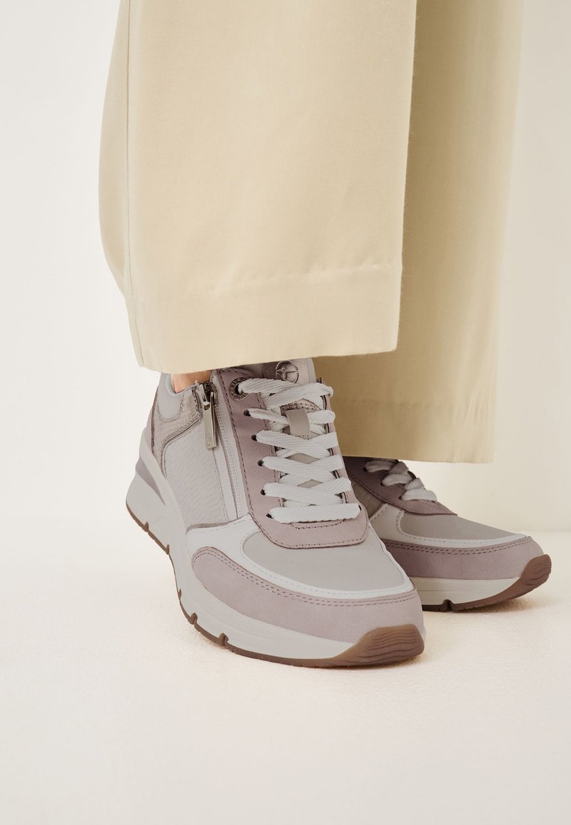 Baskets grises avec un mélange de tissu texturé et de cuir lisse, présentant des lacets blancs, une hauteur de cheville et un détail zippé sur le côté.