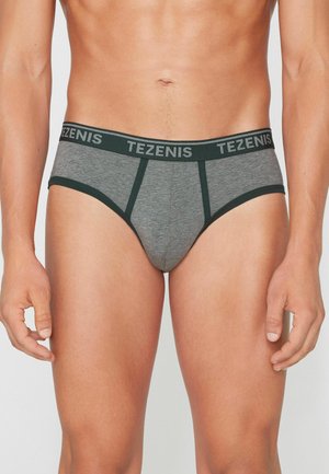 Hombre con calzoncillos grises con ribete y cintura de color verde oscuro que llevan repetido el nombre de la marca Tezenis.