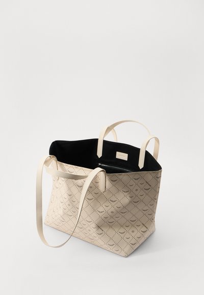Sac en toile beige avec un motif texturé, doté de deux poignées, d'un intérieur noir contrastant et d'une poche zippée intérieure.