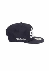 Marineblaues Snapback-Cap mit weißer Stickerei "99" und "JUDE" auf der Vorderseite, "West vs. East" auf der Seite gestickt, flaches Schirmdesign.