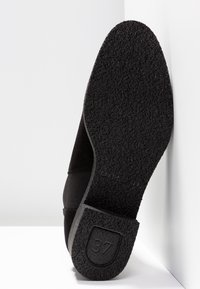 Semelle de chaussure noire avec une surface en caoutchouc texturé, dotée d'un talon carré et de la taille "37" embossée sur le côté. Design minimaliste.