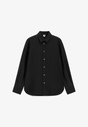 Chemise noire à manches longues avec col pointu, poignets boutonnés et ourlet arrondi, présentée sur un fond blanc.