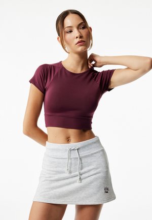 Burgundin lyhythihainen crop-top, joka on yhdistetty vaaleanharmaaseen naruhelmahuppariin, jossa on vyötärövyö, sileä kangas ja brodeerattu logo.