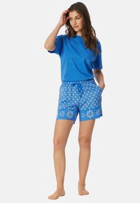Blaues Baumwoll-T-Shirt kombiniert mit blauen, gemusterten Shorts mit floralen Designs und verstellbarem Kordelzug an der Taille. Lässige, bequeme Passform.