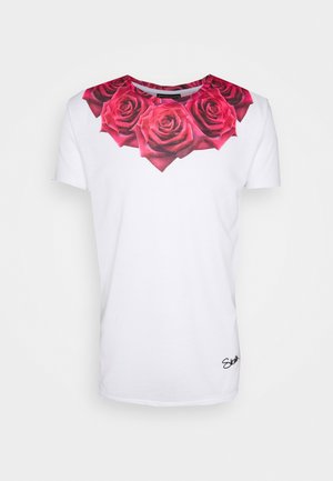 Camiseta blanca de manga corta con un vibrante racimo de rosas rojas impresas alrededor del escote y un pequeño logo en letra negra en el dobladillo inferior.