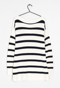 Pull en maille blanche à rayures horizontales noires suspendu à un cintre noir sur fond blanc.