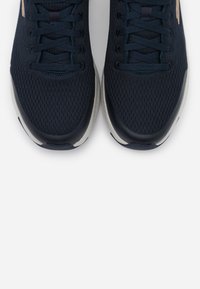 Scarpe sportive in rete di colore navy con accenti neri, dotate di punta rotonda, design con lacci e suola bianca con dettagli testurizzati.