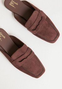 Mule in suede marrone con punta quadrata e dettaglio cucito sulla parte superiore. Soletta liscia con testo impresso. Suola piatta.