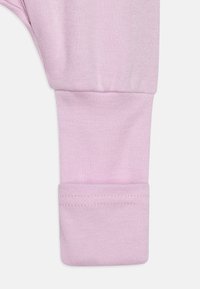 Tissu en coton rose pâle avec un design de poignet ajusté, présentant une texture lisse et des détails de couture subtils.