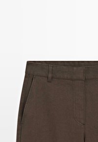 Pantaloni in cotone marrone con una linea dritta, dotati di due tasche laterali, una cintura robusta e un tessuto leggermente strutturato.