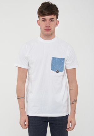 T-shirt bianco in cotone con tasca in denim blu con un design triangolare. Maniche corte e collo rotondo. Dettaglio del design frontale in evidenza.
