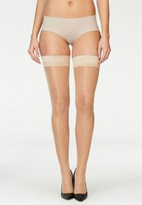 Nackte Oberschenkelstrumpfhosen mit transparenter Textur, verstärkter Spitze und satinartigem Finish, die oben von weichen, elastischen Bändern gehalten werden.