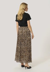 Plisseret maxi-nederdel i leopardprint, lavet af letvægtsstof, har et sort taljebånd, parret med en tætsiddende sort t-shirt og hælede mules.