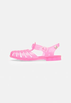 Sandal en gelée rose avec un design à fentes, une bride réglable et une semelle plate. Fabriquée en matériau plastique flexible pour plus de confort.