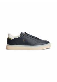 Baskets basses bleu marine avec col rembourré blanc, semelle beige, lacets noirs, œillets dorés et petit logo doré sur le côté.
