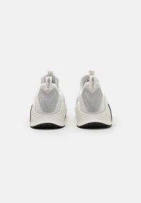 Weiße Sportschuhe mit einem Mesh-Obermaterial, strukturierten silbernen Akzenten und einer strapazierfähigen schwarzen Gummisohle. Verfügt über eine Zuglasche an der Ferse.
