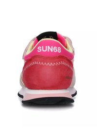 Sneaker rossa e rosa con tomaia in mesh e suede, dettagli neri, lacci luminosi e suola imbottita con una suola testurizzata.