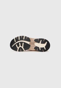 De zool van de schoen heeft een gestructureerd zwart rubberen oppervlak met lichtbeige accenten, ontworpen voor grip en stabiliteit met een gebogen vorm.