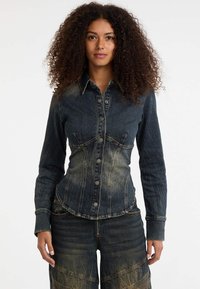 Denim shirt met een slim fit ontwerp, donkerblauwe kleur, knoopsluiting aan de voorkant, gebogen zoom en contrasterende lichte vervaging details op de borst.