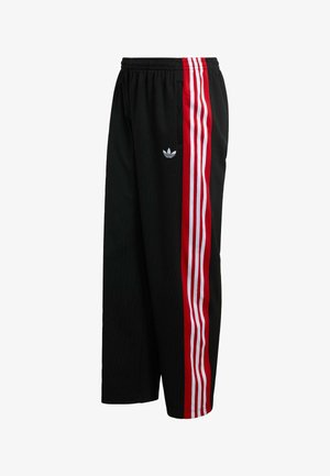 Czarne spodnie z siateczki o szerokim kroju, z czerwono-białymi paskami po bokach i małym białym logo po lewej stronie. Elastyczna talia.