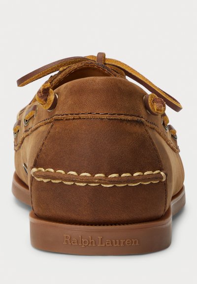 Brune lædersbådsko med rund hæl, kontraststing, metaløjer og struktureret snørebånd. Ralph Lauren-logo på sålen.