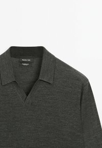 Grå merinoull polo shirt med v-ringning och korta ärmar. Etikett inte synlig; mjuk textur och klassisk design.