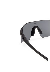 Lunettes de sport enveloppantes noires avec un seul écran de protection foncé et des plaquettes de nez réglables sur fond blanc.