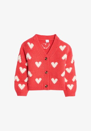 Cardigan rouge avec un col en v, motifs de cœurs blancs, fermeture à boutons et poignets côtelés. Texture tricot douce, design court.