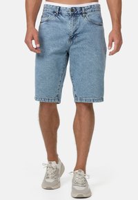 Shorts en denim bleu clair avec une coupe décontractée, ourlets retournés et design classique à cinq poches. Fermeture à bouton métallique et passants de ceinture inclus.