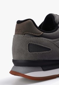 Zapatillas de ante gris con acentos de malla negra, que cuentan con una suela de goma y una entresuela gris en contraste. Sutil marca del logo en el talón.