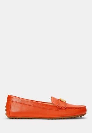 Mocasín de cuero naranja con un detalle de hebilla dorada en la parte superior y suela de caucho con textura de guijarros que se extiende hasta el talón.